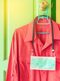 Close-up of shirt hanging on door with mask