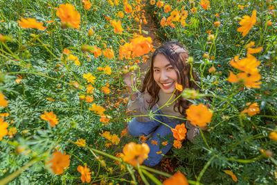 Portrait of woman crouching on land by yellow flowering plants