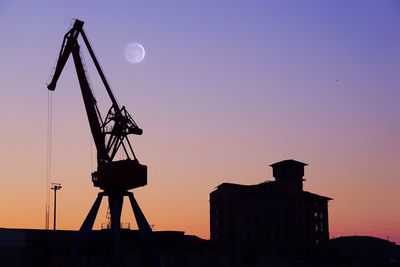 Low angle view of silhouette cranes against sky at sunset