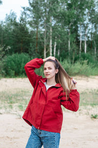 Candid portrait of a young caucasian woman in red clothes playing with her hair, posing