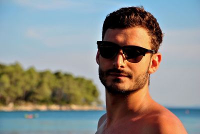 Close-up of young man wearing sunglasses against sky