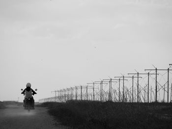 Rear view of boy riding motorcycle on field against sky