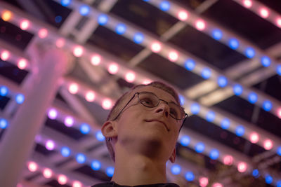 Low angle view of man against illuminated ceiling