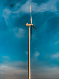 Low angle view of wind turbine against blue sky