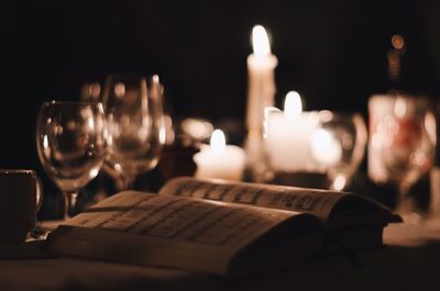 Close-up of book and illuminated candles on table