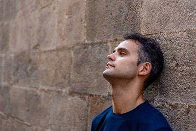 Portrait of a teenage boy looking up against wall