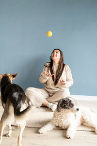 Beautiful brunette woman with playful mixed breed dog, embracing and having fun at home