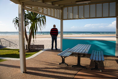 Rear view of man standing by sea against sky