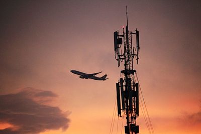 Low angle view of silhouette communications tower against sky during sunset