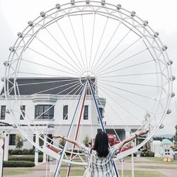 Rear view of woman with ferris wheel against sky