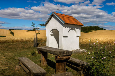 Built structure on field by houses against sky