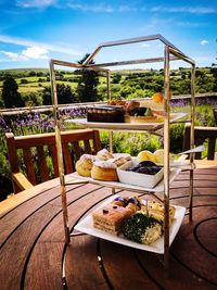 Table and chairs on railing against sky