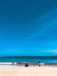 People on beach against blue sky