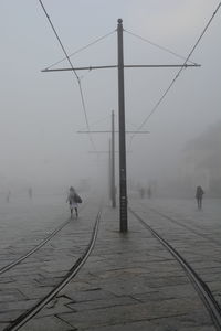 Snow covered electricity pylon against sky during foggy weather