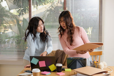 Female friends using digital tablet while sitting on table