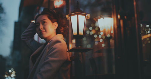 Young woman looking at illuminated window