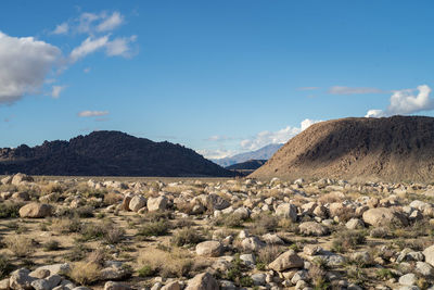 Scenic view of rocky desert valley, hills and mountains against sky