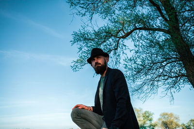 Low angle view of man crouching against sky