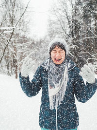 Smiling woman is playing with snow. fun in snowy winter forest. woman laughs and walks through wood. 