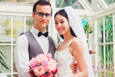 Married couple holding bouquet sitting outdoors