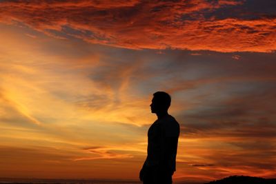 Silhouette man standing against orange sky