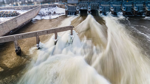 Water is rushing at the dam in winter as spring approaches with extended exposure settings