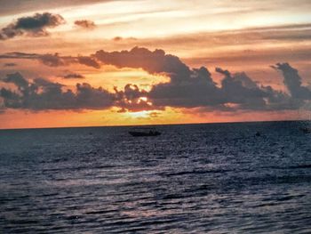 Scenic view of sea against cloudy sky during sunset