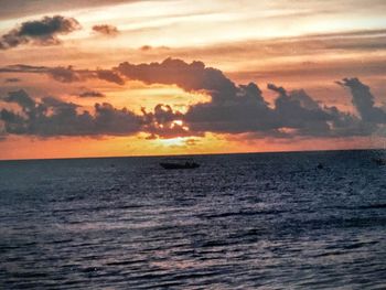 Scenic view of sea against cloudy sky during sunset