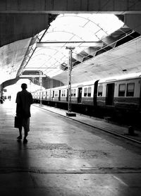 Rear view of man walking on railroad station platform