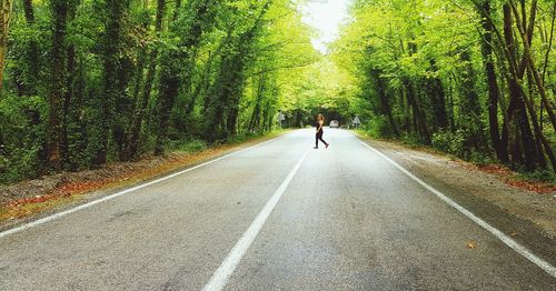 Side view of woman walking on road in forest