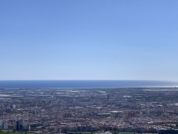 Aerial view of city by sea against clear sky