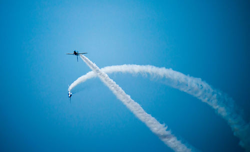 Low angle view of airplane flying against blue sky