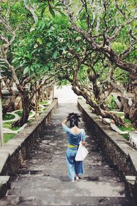 Woman walking on stairs along plants