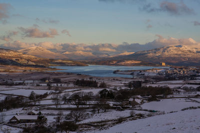 Scenic view of snow covered field by lake against sky