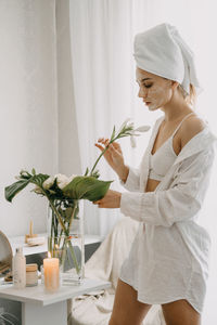 Woman holding white flowering plant at home