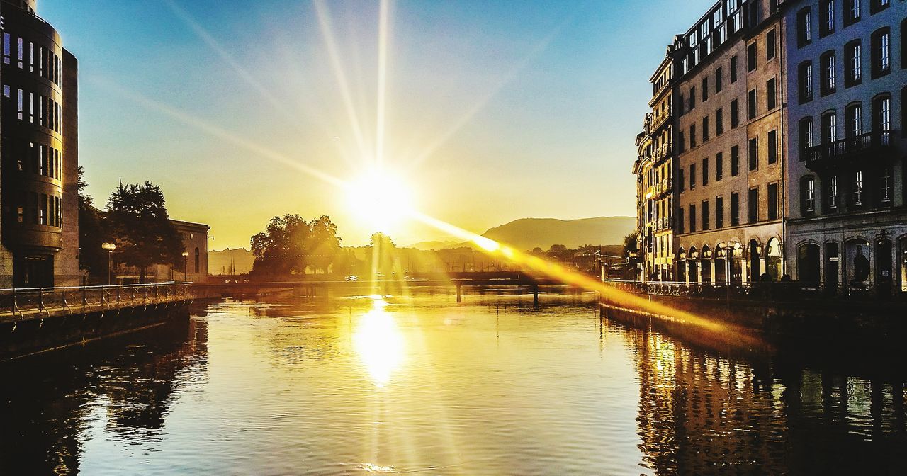 sun, building exterior, architecture, built structure, water, sunbeam, sunlight, reflection, lens flare, waterfront, city, canal, river, sky, building, sunny, sunset, bright, rippled, shiny