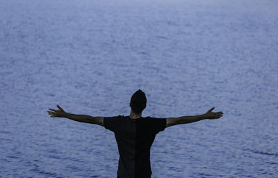 Rear view of silhouette man standing by sea