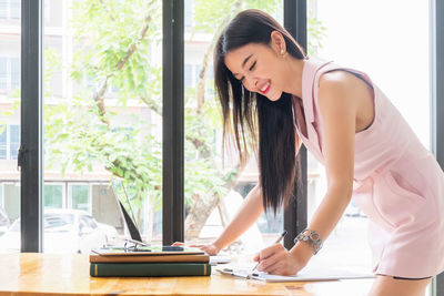 Side view of young woman on table against window