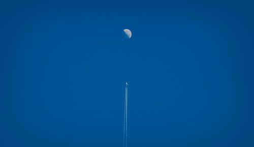 Low angle view of moon against clear blue sky