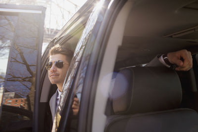 Young businessman getting out of car service limousine