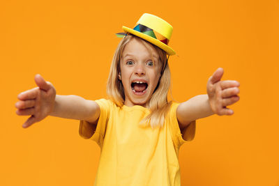 Portrait of girl screaming while standing against yellow background