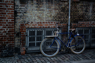 Bicycle parked by brick wall
