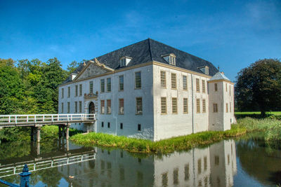 Reflection of building on lake against blue sky