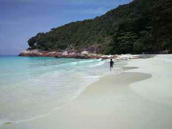 Rear view of boy running on shore at beach