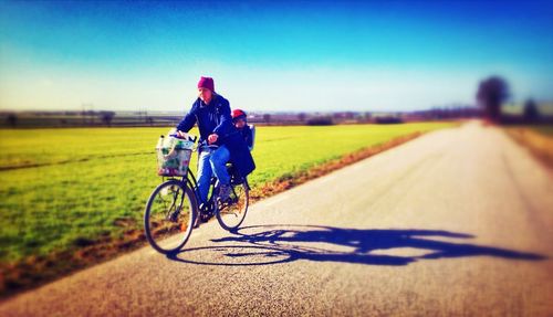 Person cycling on field against sky