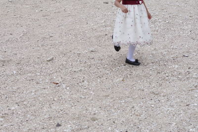 Low section of woman walking on sand