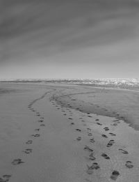 Footprints on beach against sky