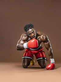 Portrait of shirtless boxer against brown background