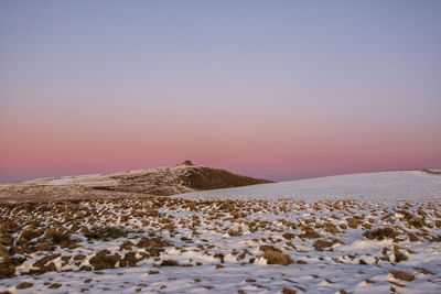 Scenic view of snow covered landscape against clear sky during sunset