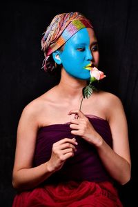 Portrait of young woman looking away over black background